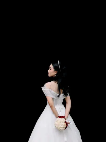 Pengantin wanita bergaun putih off-shoulder dan bertiara, membelakangi kamera, memegang mawar merah dan putih di belakang punggungnya